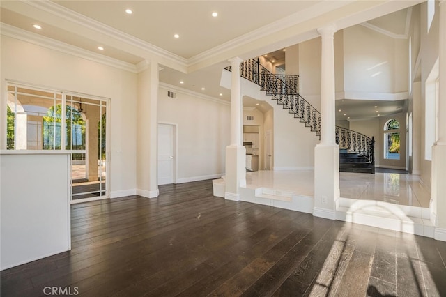 unfurnished living room featuring decorative columns, stairs, hardwood / wood-style flooring, recessed lighting, and a towering ceiling