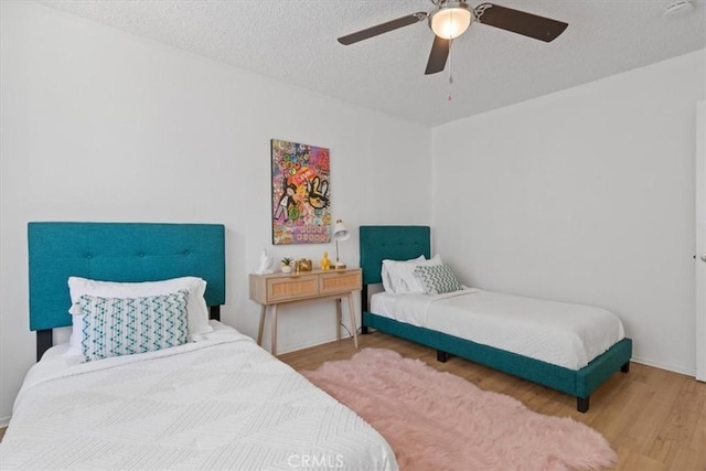 bedroom featuring wood finished floors, a textured ceiling, and ceiling fan