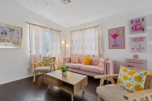 living area featuring a textured ceiling, vaulted ceiling, visible vents, and wood finished floors