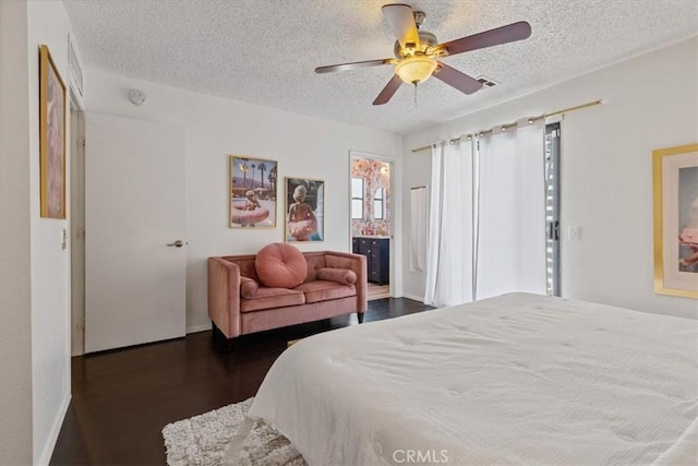 bedroom featuring a ceiling fan, a textured ceiling, baseboards, ensuite bath, and dark wood-style flooring