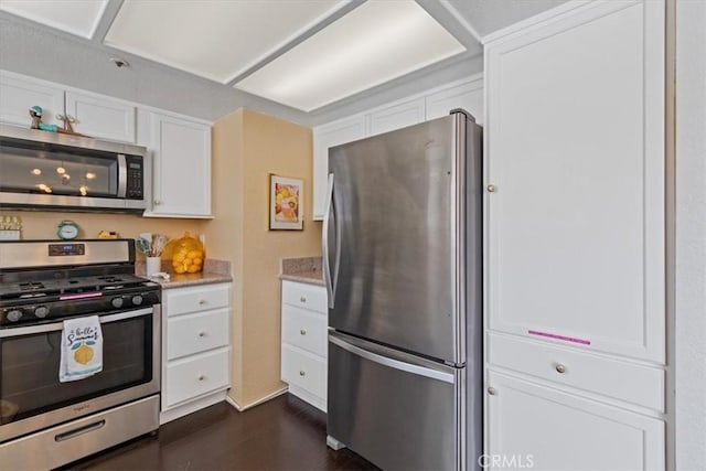 kitchen with stainless steel appliances, dark wood-style floors, baseboards, white cabinetry, and light stone counters