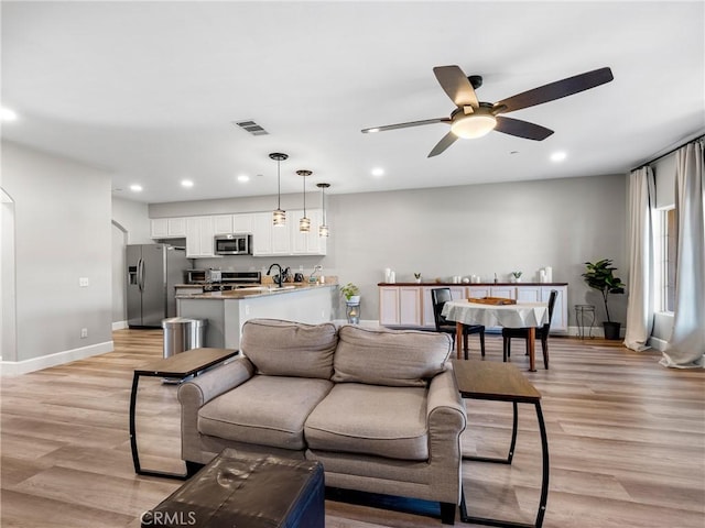 living area with recessed lighting, visible vents, light wood-type flooring, baseboards, and ceiling fan