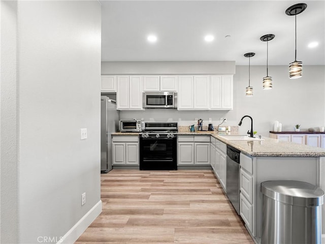 kitchen with white cabinets, a peninsula, stainless steel appliances, and a sink