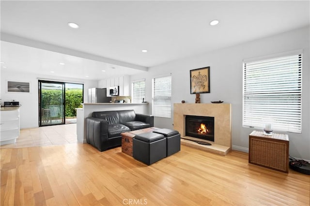 living room featuring light wood finished floors, recessed lighting, and a fireplace