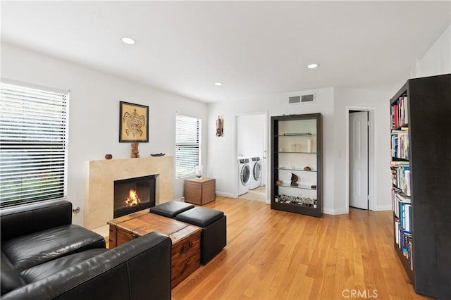 living room with light wood-style flooring, visible vents, separate washer and dryer, recessed lighting, and a fireplace