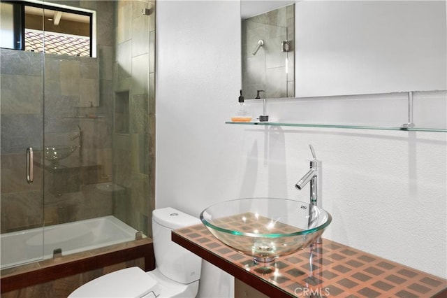 full bath featuring combined bath / shower with glass door, toilet, and a sink