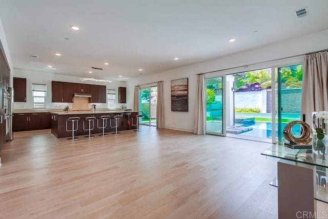6222 Artisan Way, San Diego, CA 92130 - kitchen featuring dark brown cabinetry, light countertops, under cabinet range hood, visible vents, and a center island with sink