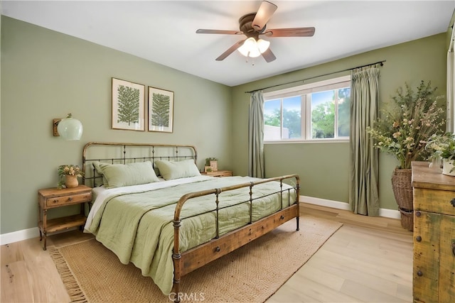 bedroom with light wood-type flooring, baseboards, and a ceiling fan