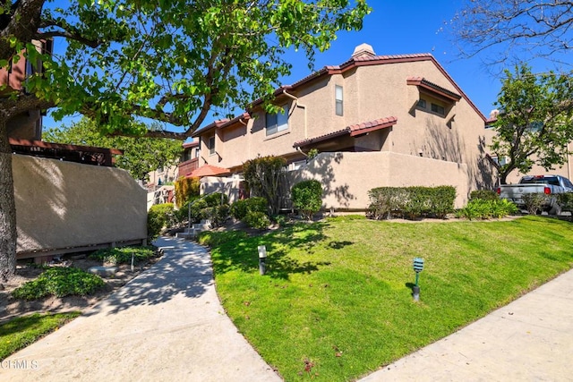 2441 Chandler Ave Unit 2, Simi Valley, CA 93065 - view of property exterior with stucco siding, a chimney, a tiled roof, and a lawn