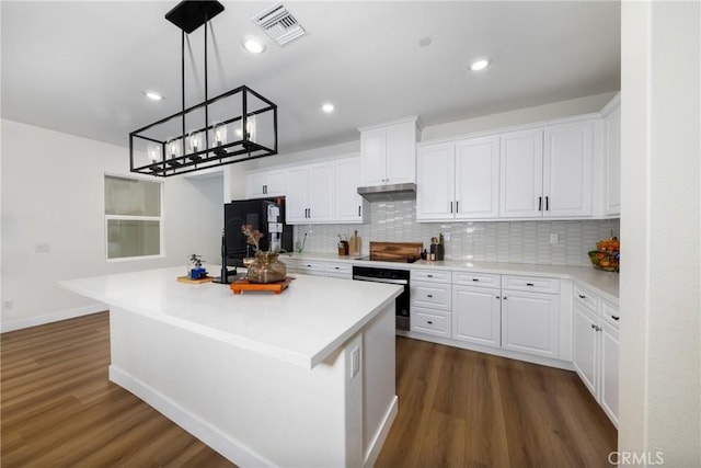 kitchen featuring freestanding refrigerator, oven, visible vents, and dark wood-style floors