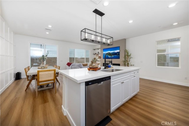 kitchen with an island with sink, light countertops, dishwasher, a sink, and light wood-style flooring