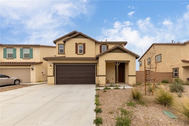 view of front of home with stucco siding, a tiled roof, a garage, and concrete driveway