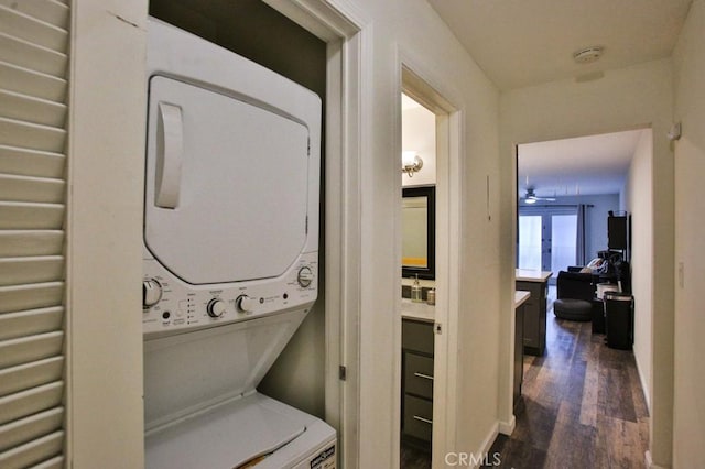 laundry room with stacked washing maching and dryer, laundry area, and dark wood finished floors