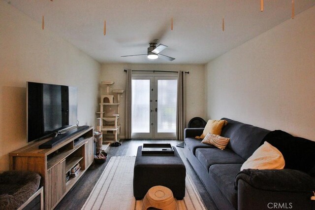 living room featuring dark wood-type flooring, a ceiling fan, and french doors