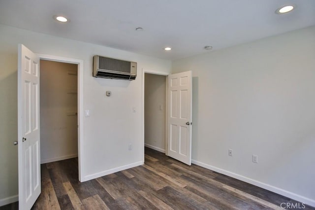 17200 Newhope St Unit 206, Fountain Valley, CA 92708 - unfurnished bedroom with a wall unit AC, a spacious closet, dark wood-type flooring, recessed lighting, and a closet