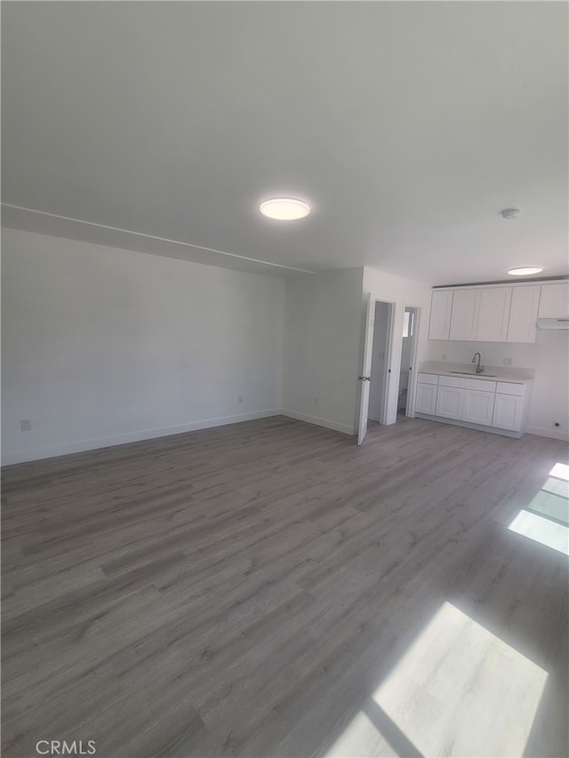 6221 Fishburn Ave, Bell, CA 90201 - unfurnished living room featuring baseboards, a sink, and light wood-style floors