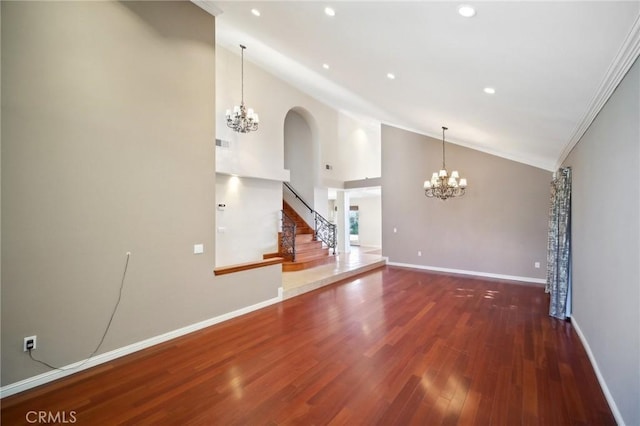 unfurnished living room with visible vents, baseboards, a chandelier, wood finished floors, and crown molding