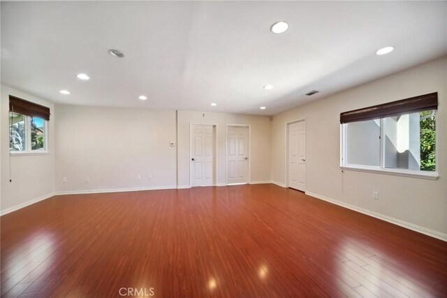 unfurnished room with baseboards, wood finished floors, visible vents, and recessed lighting