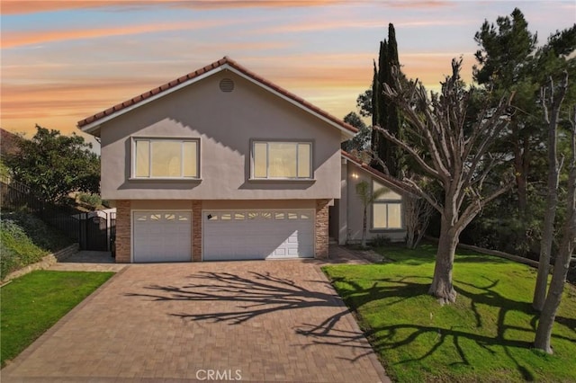 view of front of home featuring stucco siding, a front yard, decorative driveway, and a garage