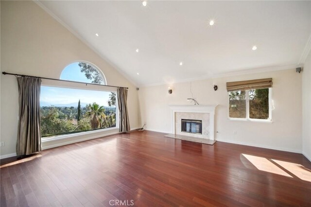 unfurnished living room featuring baseboards, high vaulted ceiling, wood finished floors, a fireplace, and ornamental molding