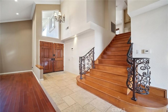foyer with visible vents, crown molding, baseboards, and a towering ceiling