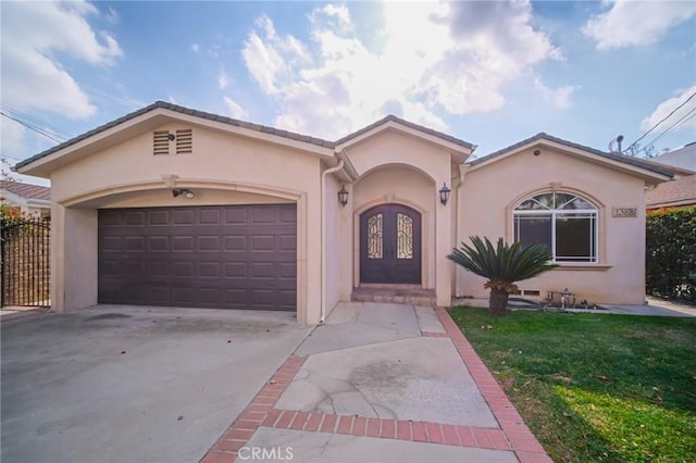 mediterranean / spanish house featuring stucco siding, driveway, a front yard, and a garage