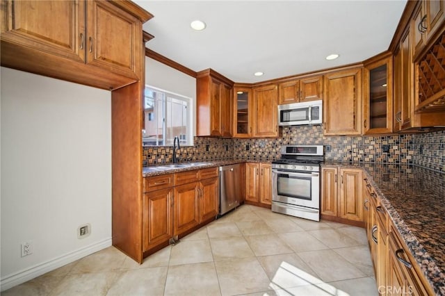 kitchen with brown cabinets, appliances with stainless steel finishes, tasteful backsplash, and a sink