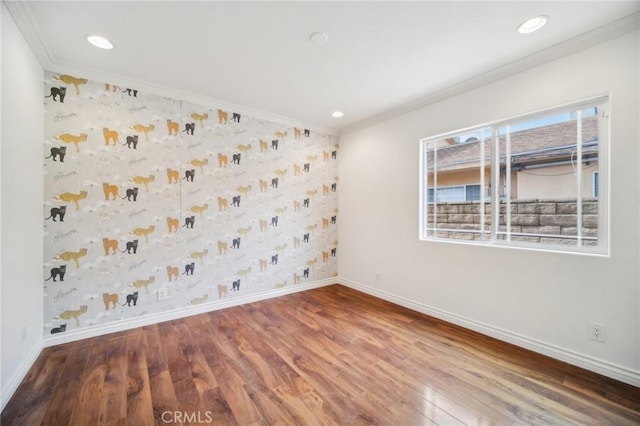 unfurnished room with wallpapered walls, wood finished floors, baseboards, and crown molding