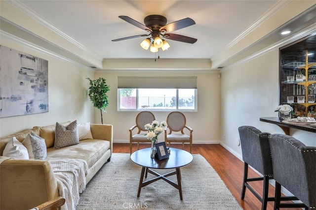 living room with baseboards, ceiling fan, wood finished floors, and a tray ceiling