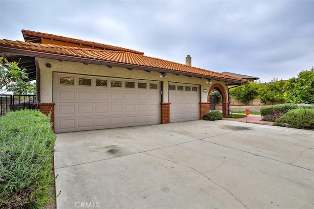 view of front of house with fence, stucco siding, a chimney, an attached garage, and driveway