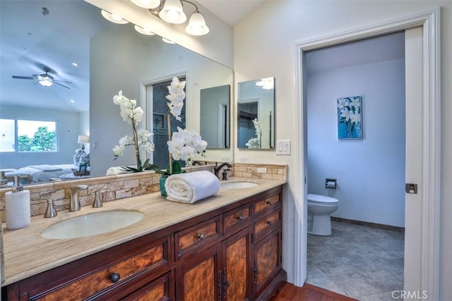 bathroom featuring double vanity, toilet, a ceiling fan, and a sink