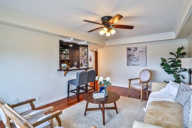 living area featuring crown molding, a ceiling fan, baseboards, and wood finished floors