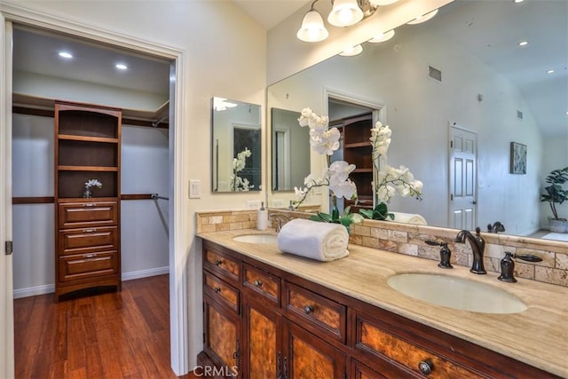 full bath featuring vaulted ceiling, a sink, visible vents, and wood finished floors