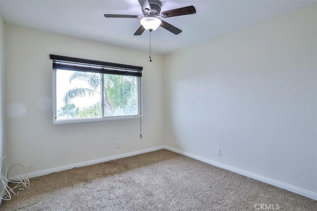 carpeted spare room with ceiling fan and baseboards