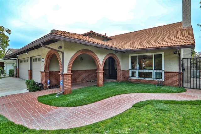 view of front of home with driveway, a front yard, brick siding, an attached garage, and stucco siding
