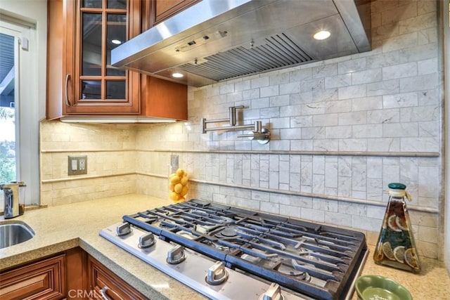 kitchen featuring brown cabinetry, tasteful backsplash, exhaust hood, and stainless steel gas stovetop