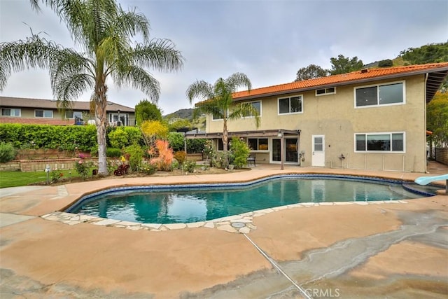 pool with a patio, a diving board, and fence