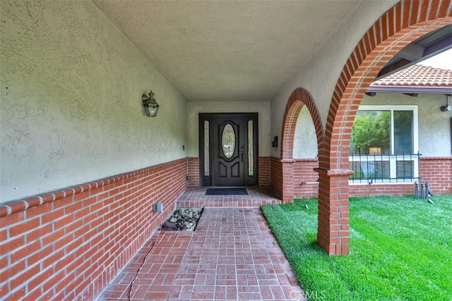 view of exterior entry with brick siding and stucco siding
