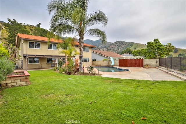 back of property with a fenced backyard, a fenced in pool, a patio area, a mountain view, and a yard