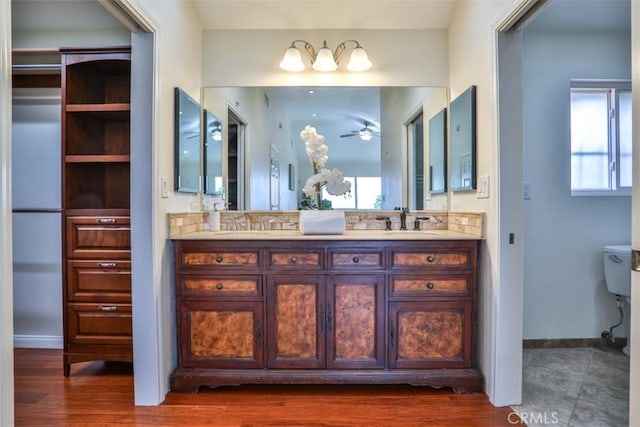 bathroom with double vanity, a ceiling fan, a sink, baseboards, and toilet
