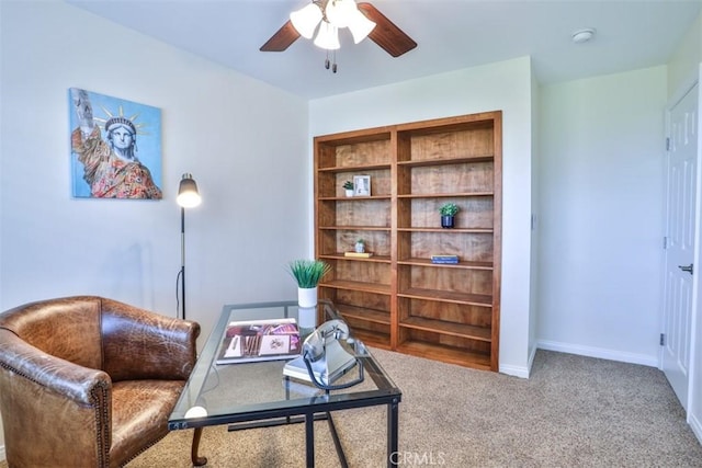 living area with baseboards, carpet, and a ceiling fan