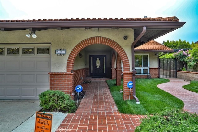 entrance to property with brick siding, a garage, stucco siding, and driveway