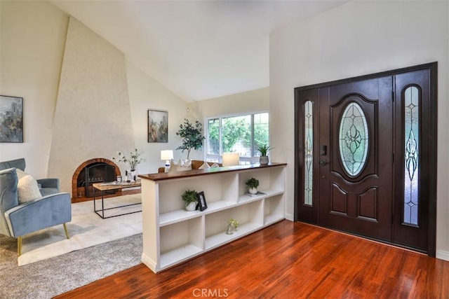 foyer with wood finished floors and high vaulted ceiling