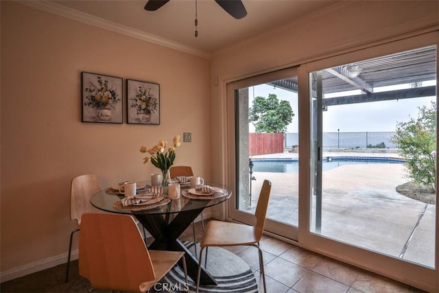 tiled dining space featuring a ceiling fan, baseboards, and ornamental molding