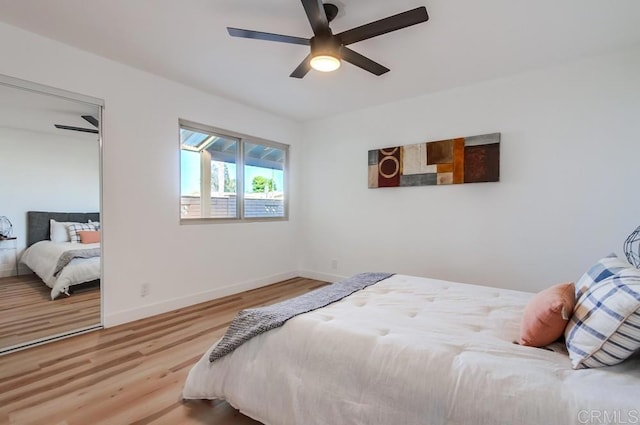 bedroom featuring baseboards, wood finished floors, a closet, and ceiling fan