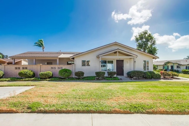 ranch-style home featuring stucco siding, fence, and a front lawn