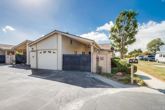 view of front of property featuring fence, an attached garage, driveway, and a gate