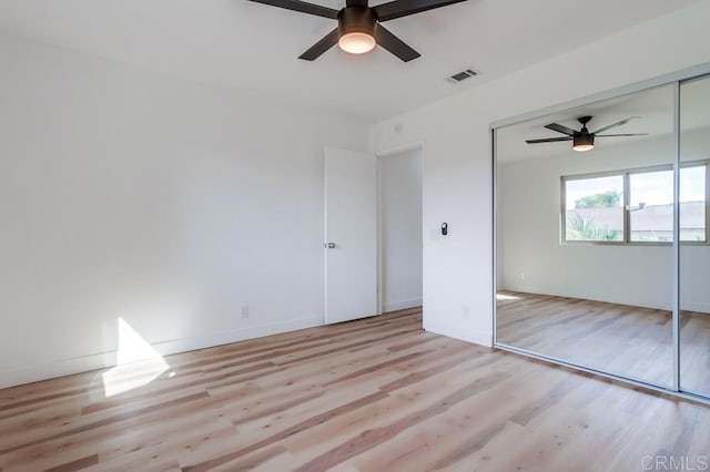 unfurnished bedroom featuring ceiling fan, wood finished floors, visible vents, and a closet