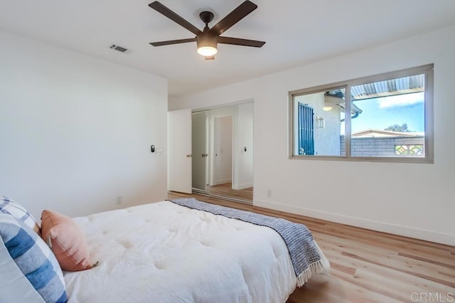 bedroom with a closet, baseboards, a ceiling fan, visible vents, and wood finished floors