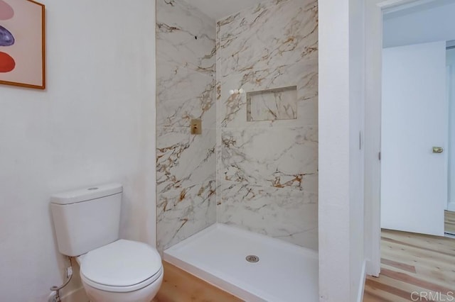 bathroom with a shower stall, toilet, and wood finished floors
